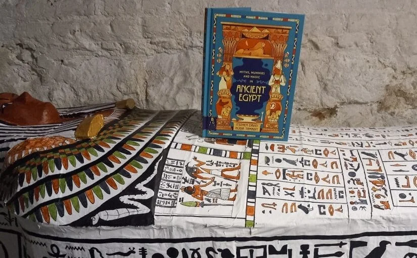 Myths Mummies and Magic book standing on a papier mache Egyptian coffin